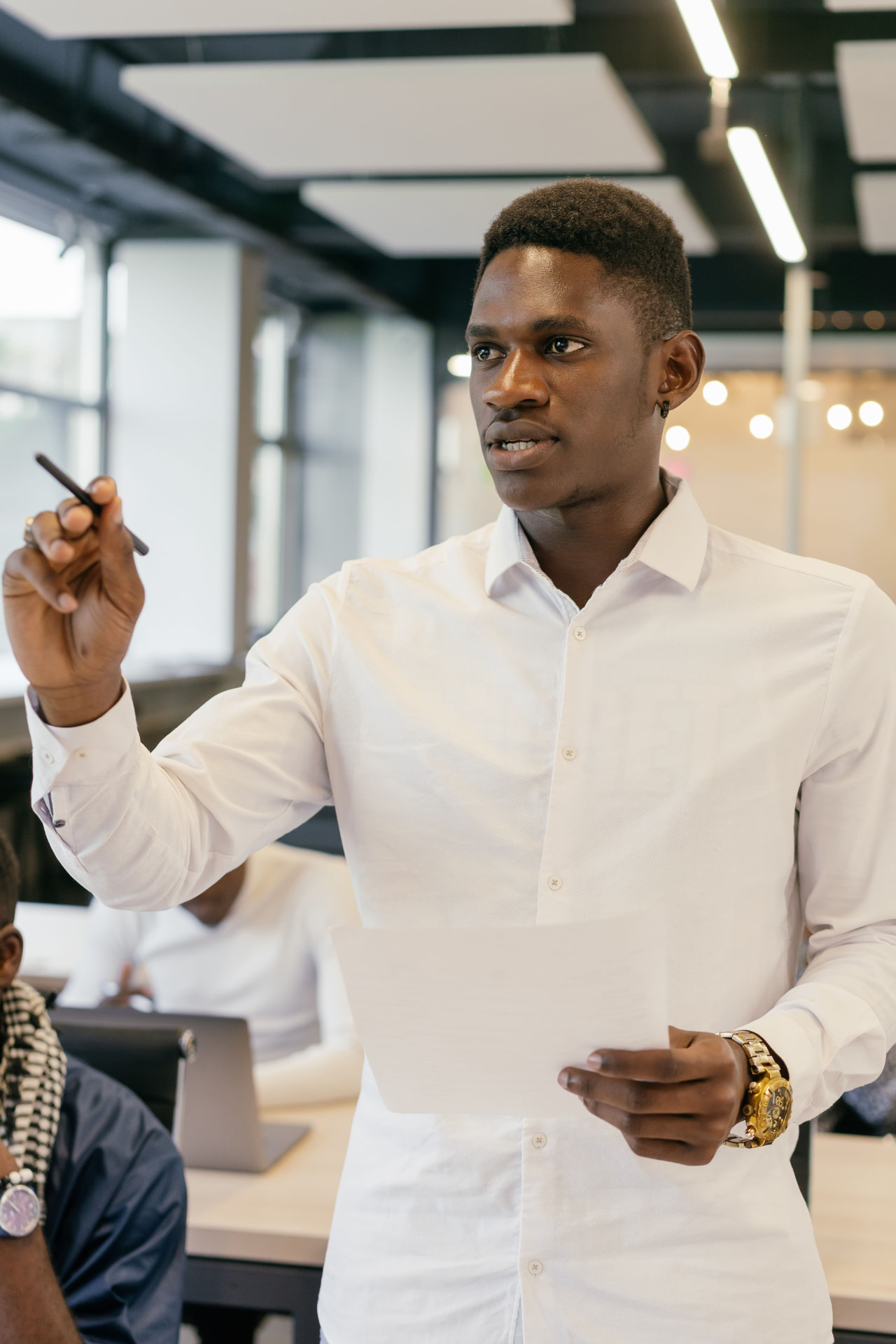 Young African leader presenting confidently to his team in a modern office